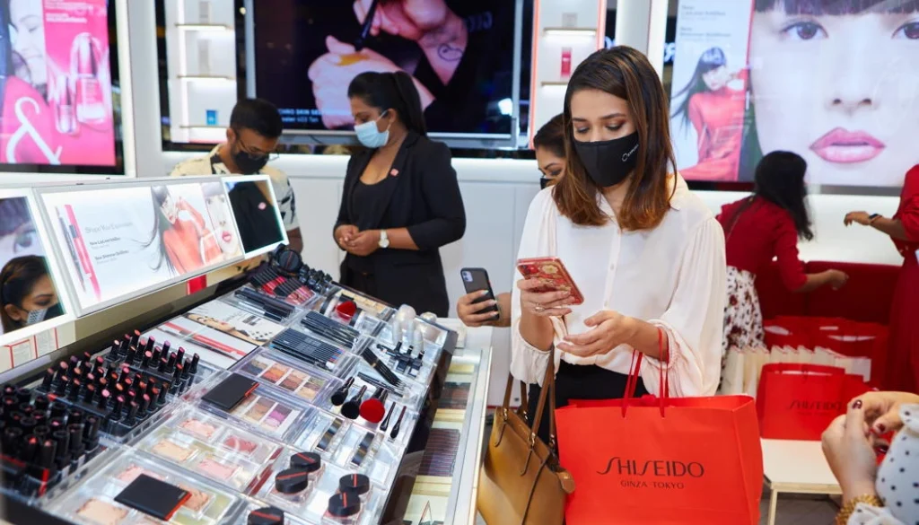Shoppers browse luxury beauty products at a Shiseido store with staff assisting and promotional displays visible.